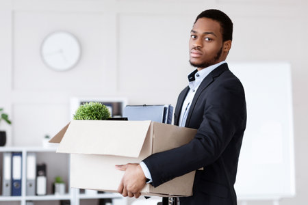 Young black man got fired, holding box with his belongings