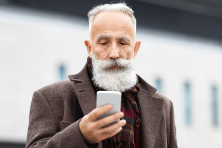 Wealthy senior man checking his modern smartphoneの写真素材