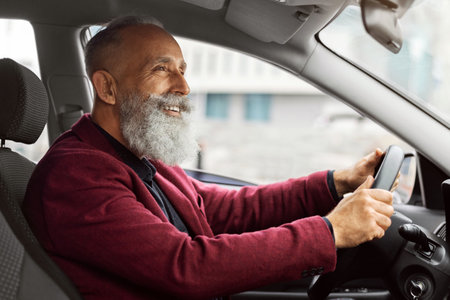 Joyful elderly grey-haired man driving new car, traveling alone