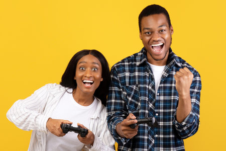 African american young couple express emotions of success and play with joystick in online game
