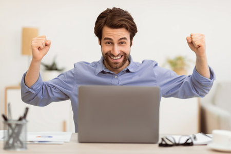 Man At Laptop Celebrating Business Success In Officeの写真素材