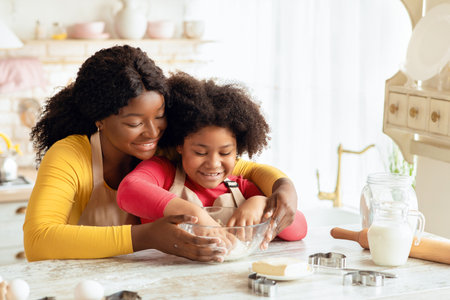 Happy Family In Kitchen. Black Mother And Little Ddaughter Preparing Dough Togetherの写真素材