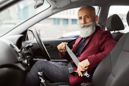 Senior man in suit fasten seat belt in his car