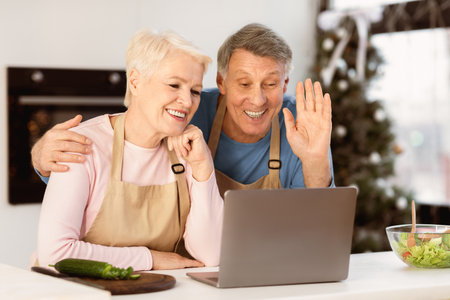 Happy Senior Couple At Laptop Making Video Call In Kitchen