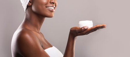 Cream jar on open palm of smiling african american womanの写真素材