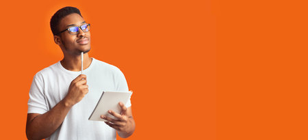 Pensive black guy portrait on orange backgroundの写真素材