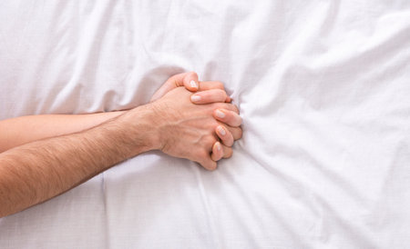 Young male and female hands on bed, closeupの写真素材