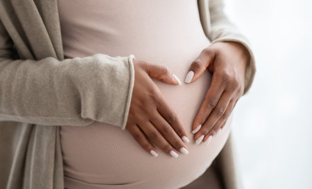 Pregnant black woman holding palms in heart shape on tummy