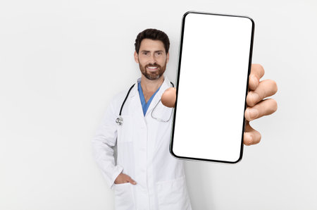 Medical App. Handsome Male Physician In Uniform Demonstrating Big Blank Smartphoneの写真素材