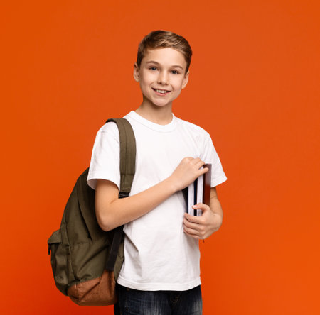 Teen boy ready for getting education, smiling with books and backpackの写真素材