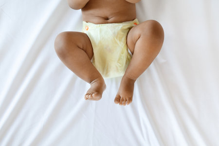 Little African American Baby Wearing Reusable Diaper Lying On Bed, Cropped Shotの写真素材