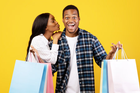 Surprised young african american guy with open mouth shows many color packagesの写真素材