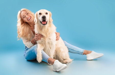 Young woman sitting with her dog at blue studioの写真素材