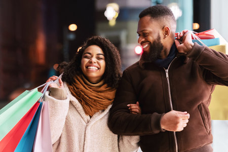 Portrait of happy afro couple walking with shopping bagsの写真素材