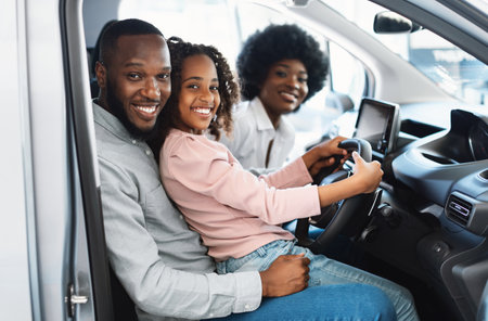 Happy Afro family sitting in new car, going on test drive, buying automobile in dealership storeの写真素材