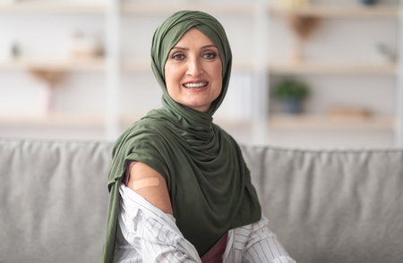 Happy Vaccinated Muslim Woman Showing Arm With Plaster Bandage Indoor
