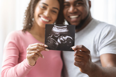 Happy expecting couple showing ultrasound image of their babyの写真素材