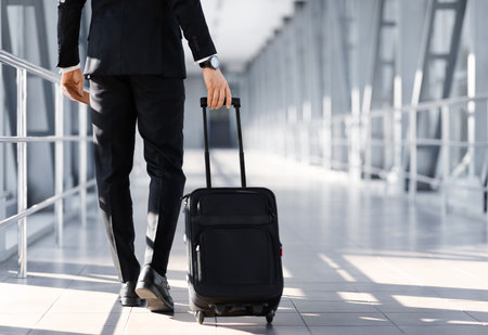 Unrecognizable entrepreneur in suit walking by airport, holding passportの写真素材