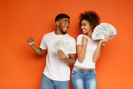 Cheerful african-american man and woman enjoying lots of moneyの写真素材