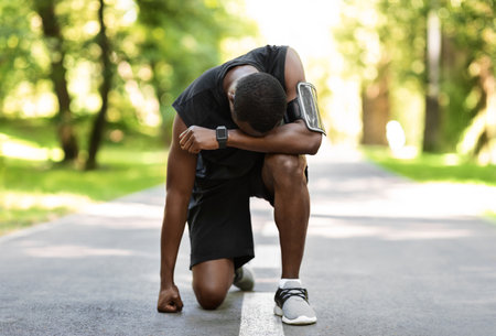 Upset african sportsman standing on park pathの写真素材