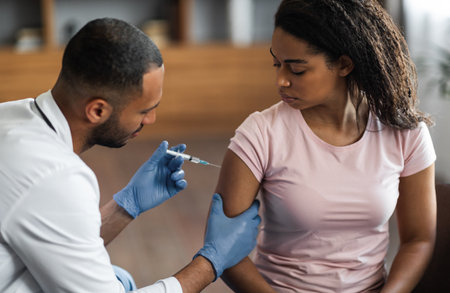 Handsome black man making injection in shoulder for female patientの写真素材