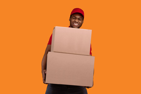 Black delivery man holding pile of boxesの写真素材