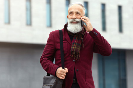 Stylish senior man talking on phone, comming back from officeの写真素材