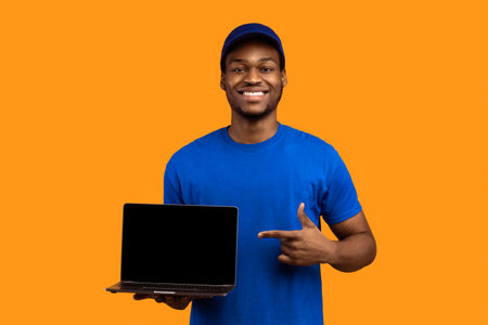 Black delivery man holding laptop with blank screen for mockupの写真素材