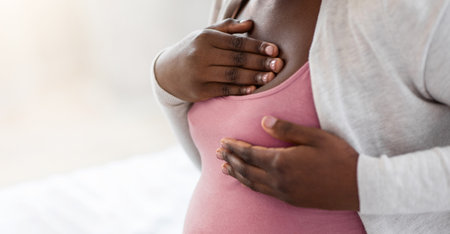 Pregnancy Discomfort. Black pregnant woman suffering painful feelings in breast, massaging herselfの写真素材