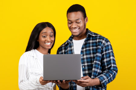 Happy millennial african american couple looking at laptop and choosing purchase or watch lesson or videoの写真素材