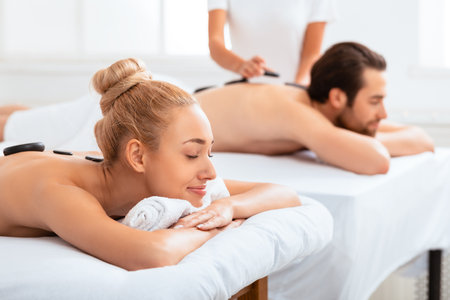 Couple Receiving Hot Stone Massage Enjoying Beauty Treatment Indoorsの写真素材