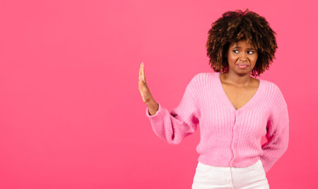 Sad confused millennial african american curly woman in casual show hand stop sign, isolated on pink backgroundの写真素材