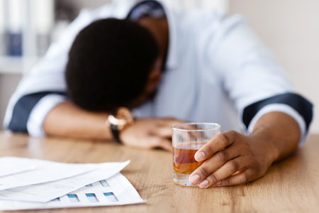 Stressed african american businessman drinking whiskey in workplace