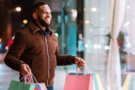 Black guy with shopping bags looking at mallの写真素材