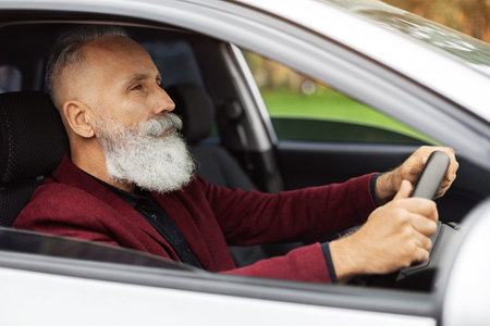 Concentrated senior man driving car, side viewの写真素材