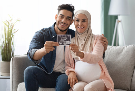 Pregnant Islamic Lady And Her Husband Showing Baby Sonogram Picture At Cameraの写真素材