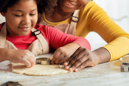 Cute little black girl making cookies with mom in kitchen togetherの写真素材