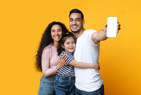 Cheerful Arab Family Of Three Demonstrating Blank Smartphone With White Screen