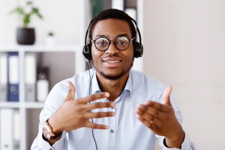 Portrait of african american guy in headset talking and gesturingの写真素材