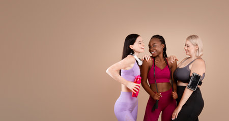Diverse body positive females in sportswear laughing and posing together