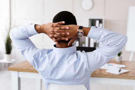 Back view of black businessman sitting at workplace in officeの写真素材