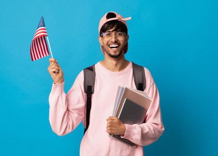 Smiling indian guy student showing flag of USの写真素材