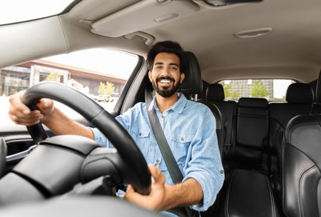 Joyful young indian man driving car, shot from dashboard