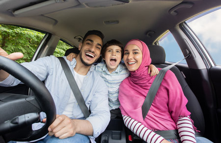 Road Fun. Joyful Muslim Family Of Three Singing In Car Togetherの写真素材