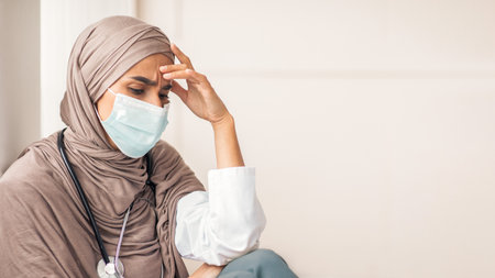 Fatigued physician young woman in hijab resting at her cabinetの写真素材