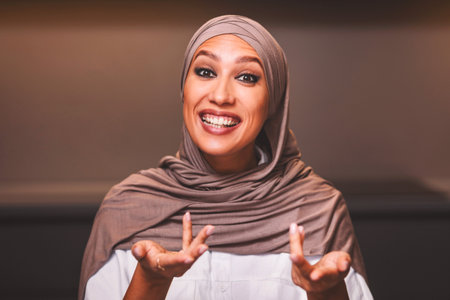 Arabic Woman Talking To Camera Making Video Sitting In Kitchenの写真素材