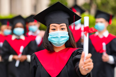 Asian young lady student in graduation costume and face mask
