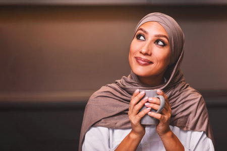Arab Lady Drinking Coffee Dreaming Looking Aside Sitting In Kitchenの写真素材