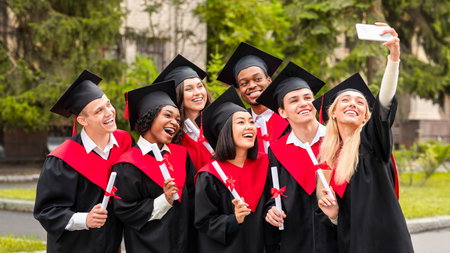 Happy graduates taking selfie together at university campusの写真素材