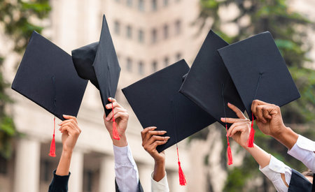 Cropped of students raising up hands with capsの写真素材
